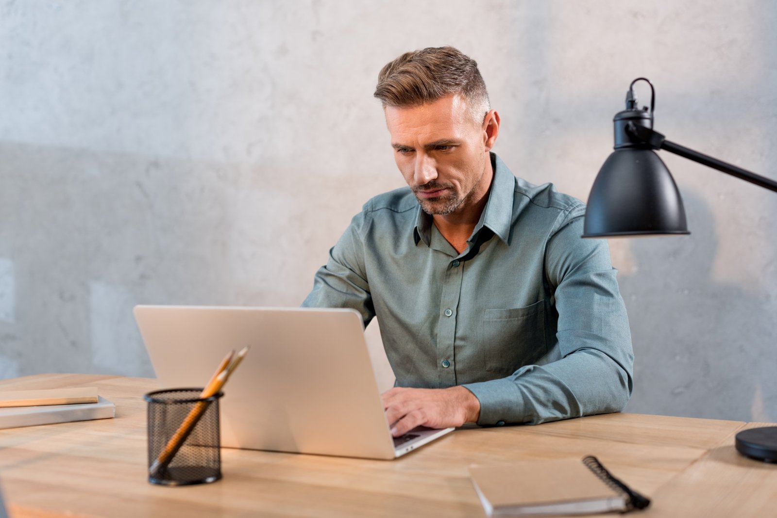 Handsome Man Sitting At Desk And Using Laptop In O 2023 11 27 04 56 34 Utc 1 1